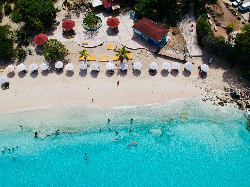 Aerial view of a white sand beach with umbrellas and turquoise water