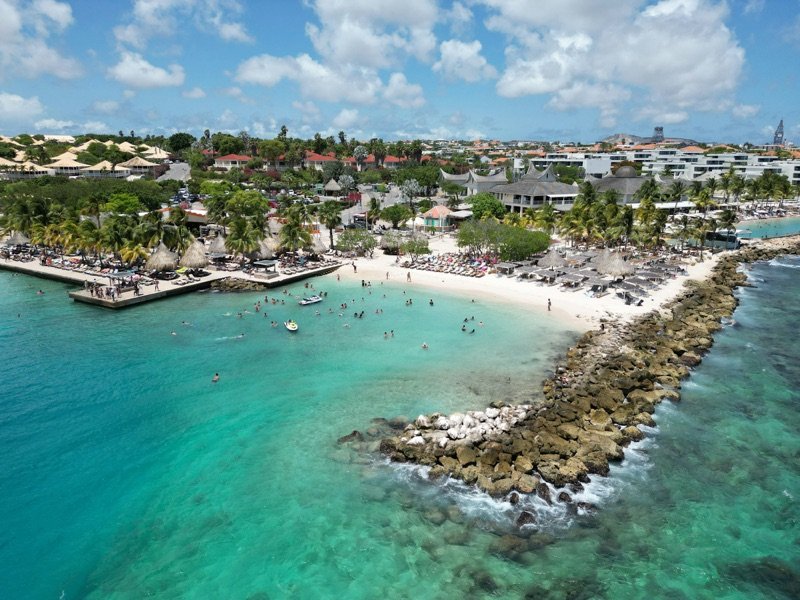 Aerial view of a beach with a pier and boats in turquoise water